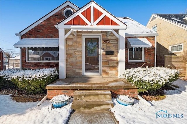 property entrance with stone siding, brick siding, and covered porch