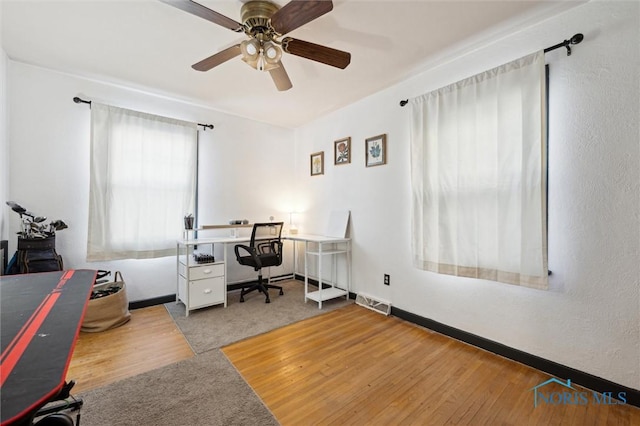 carpeted office space featuring wood finished floors, a ceiling fan, and visible vents