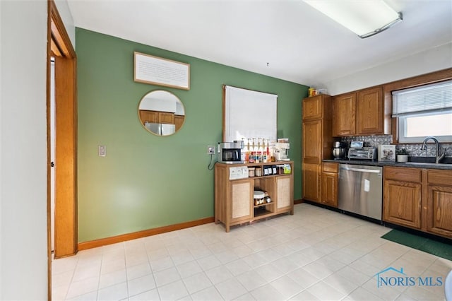 kitchen featuring dark countertops, brown cabinets, dishwasher, and a sink