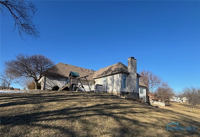 back of house featuring a yard and a chimney