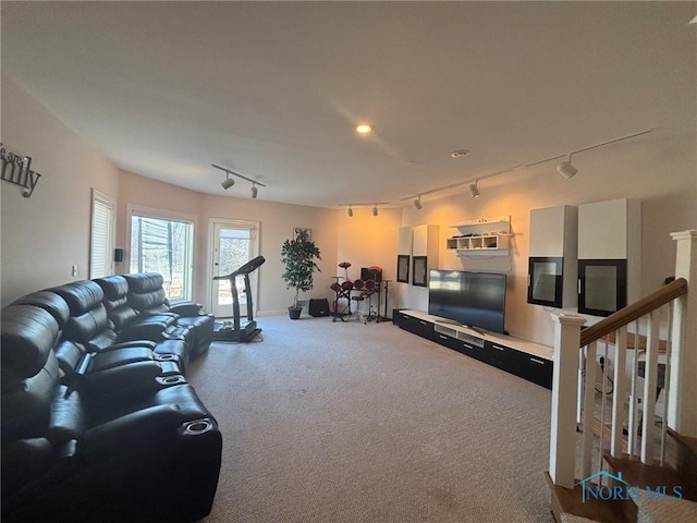 living area with stairs, rail lighting, and carpet