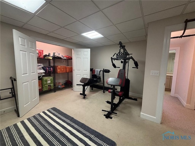 workout area with a paneled ceiling, baseboards, and carpet floors