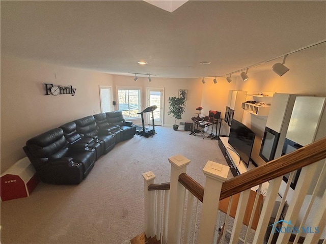 living area with carpet flooring, rail lighting, and stairway