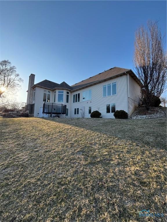 rear view of house featuring a lawn and a chimney