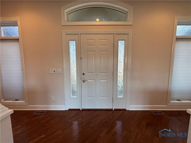 foyer featuring visible vents, dark wood-type flooring, and baseboards