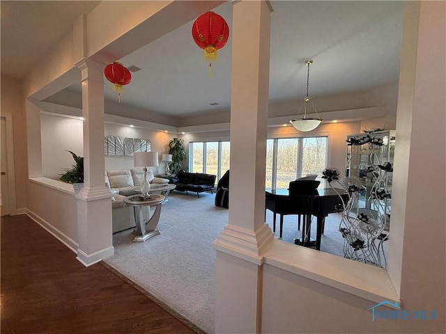 carpeted living area with decorative columns, baseboards, and wood finished floors