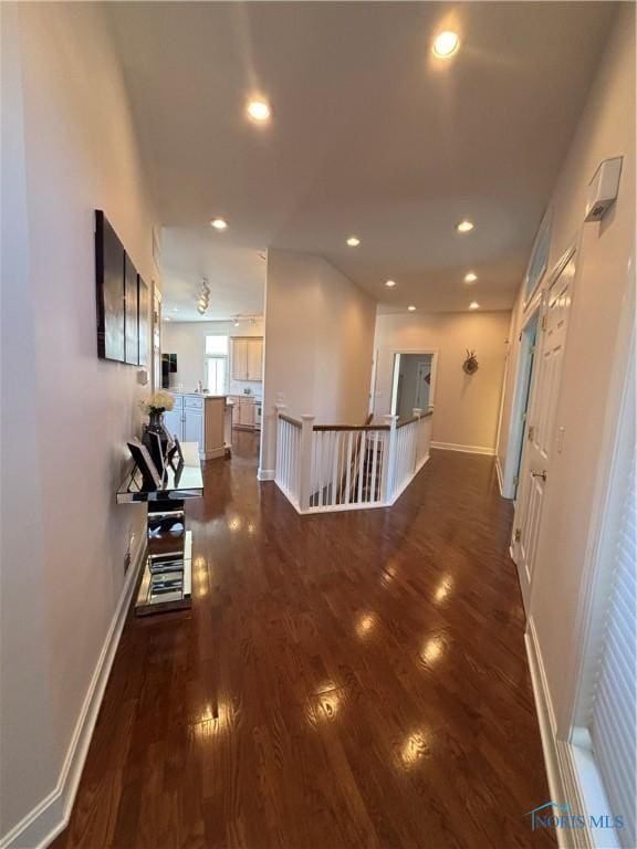 corridor featuring recessed lighting, baseboards, dark wood-type flooring, and an upstairs landing