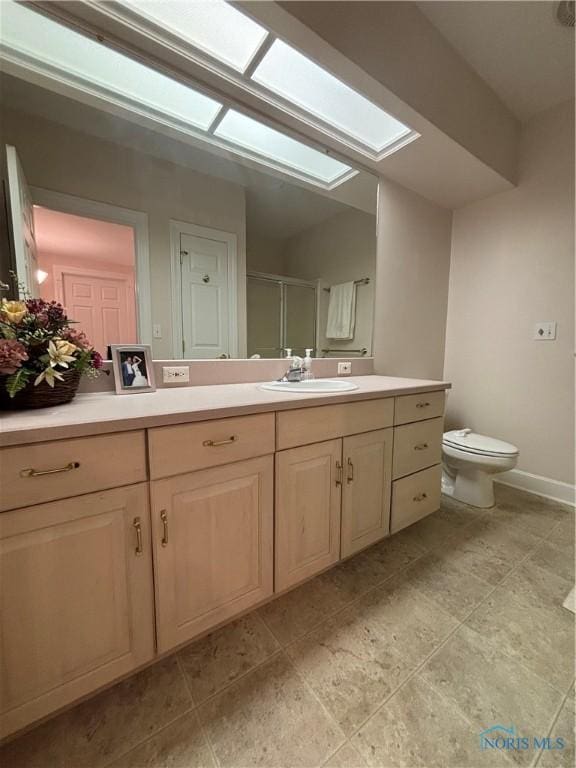 full bath featuring baseboards, toilet, a stall shower, a skylight, and vanity