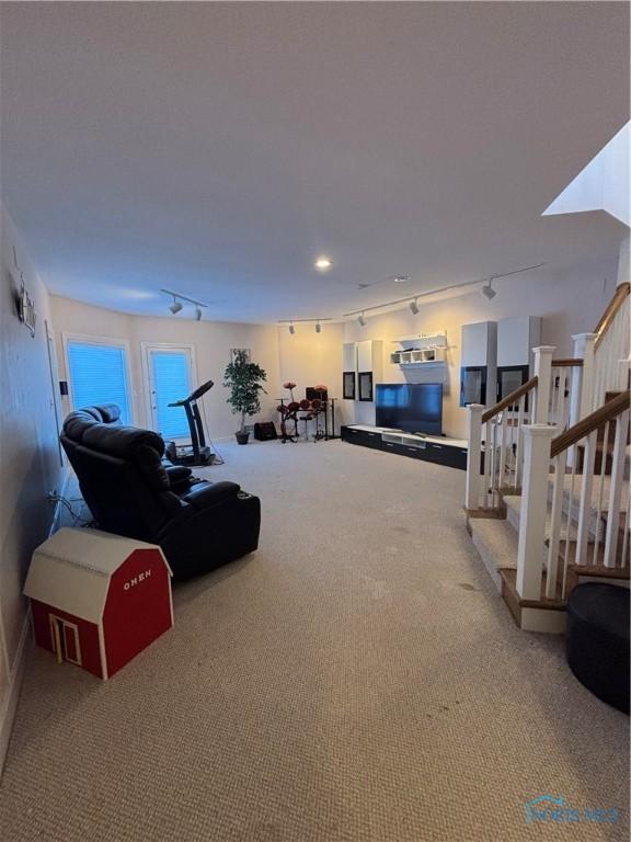 living room with rail lighting, carpet flooring, and stairs