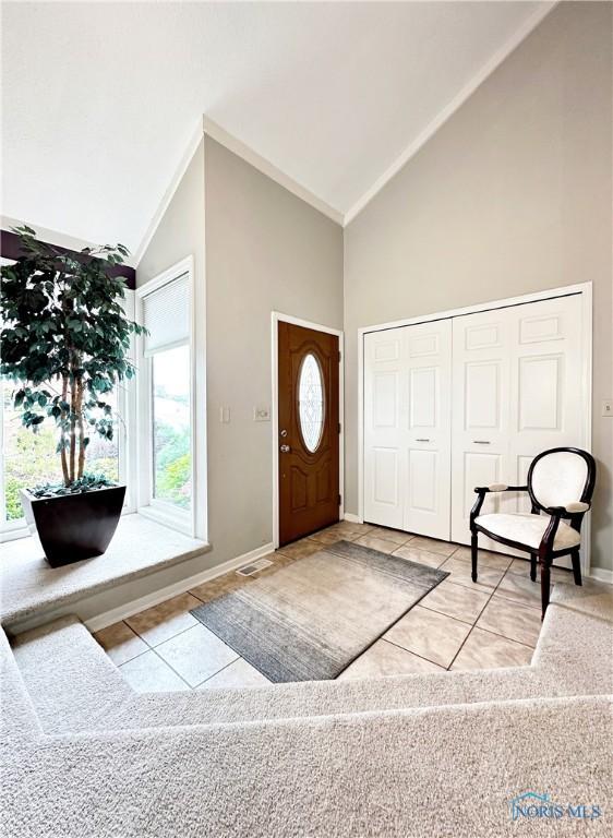 entryway with visible vents, baseboards, high vaulted ceiling, and tile patterned flooring