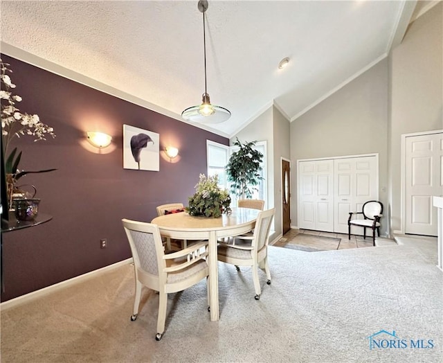 carpeted dining area featuring crown molding, baseboards, and high vaulted ceiling