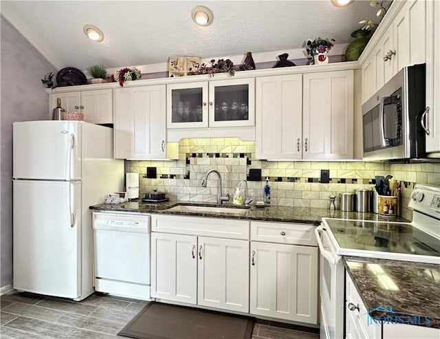 kitchen featuring backsplash, white cabinets, white appliances, and a sink