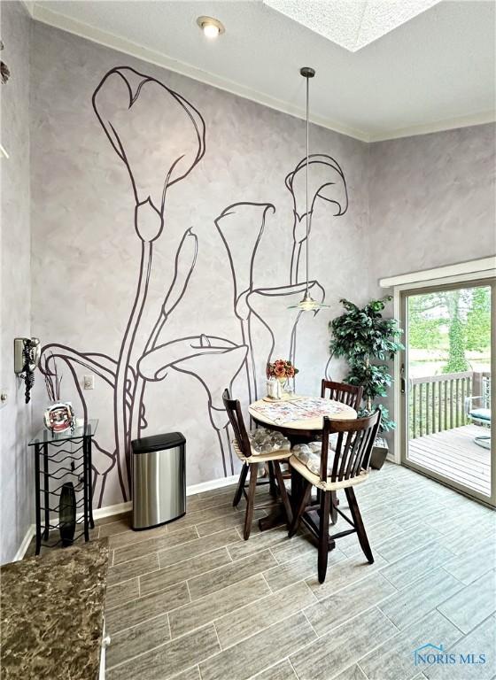 dining room with ornamental molding, baseboards, and wood tiled floor