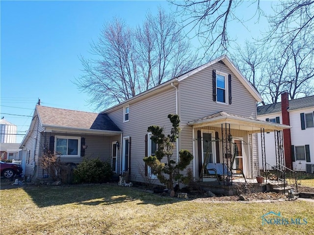 traditional-style home featuring covered porch, a front yard, and roof with shingles