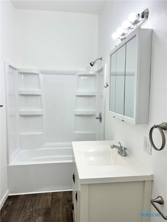 bathroom featuring vanity, bathtub / shower combination, and wood finished floors