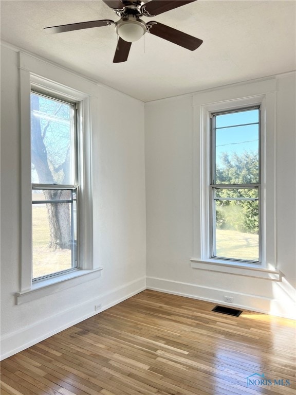 empty room featuring visible vents, baseboards, and wood-type flooring