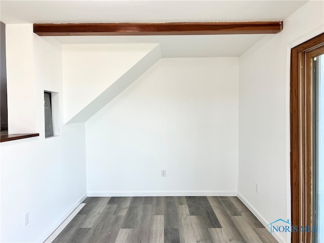 unfurnished room featuring baseboards, beam ceiling, and dark wood-type flooring