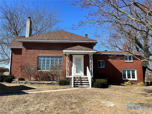 view of front facade featuring brick siding and a chimney