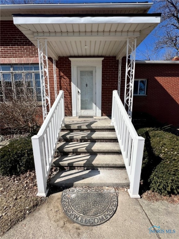 doorway to property with brick siding and covered porch