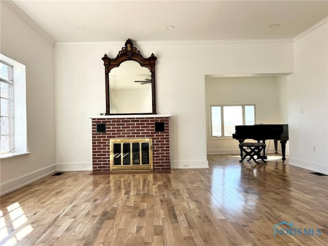 living room with visible vents, crown molding, baseboards, a fireplace, and wood finished floors