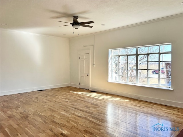 empty room featuring a wealth of natural light, hardwood / wood-style floors, and ornamental molding