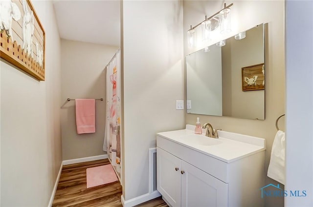 bathroom with curtained shower, baseboards, wood finished floors, and vanity