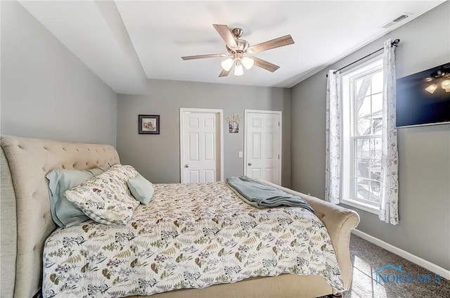 carpeted bedroom featuring visible vents, multiple windows, baseboards, and ceiling fan