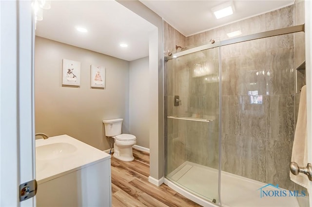 bathroom featuring vanity, toilet, wood finished floors, and a stall shower