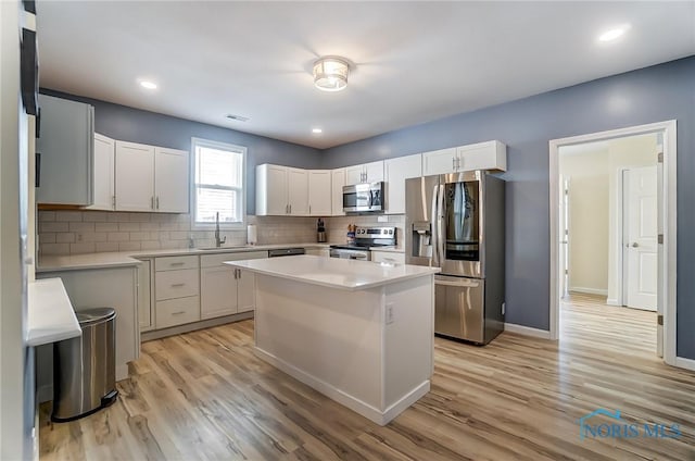 kitchen with tasteful backsplash, light wood-style flooring, appliances with stainless steel finishes, and light countertops