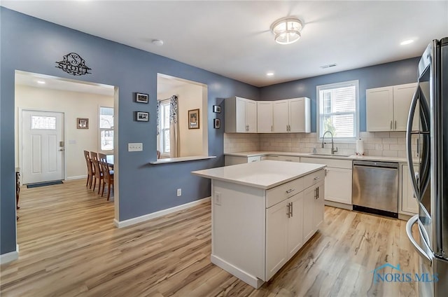 kitchen with a sink, stainless steel appliances, light countertops, and light wood finished floors