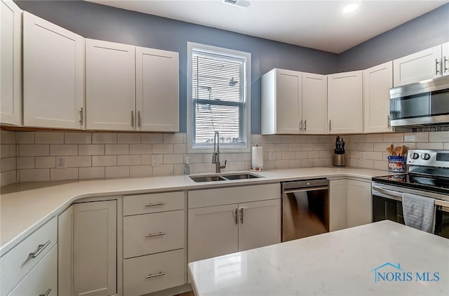 kitchen with a sink, decorative backsplash, appliances with stainless steel finishes, and light countertops