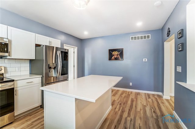 kitchen featuring visible vents, stainless steel appliances, white cabinets, light countertops, and decorative backsplash