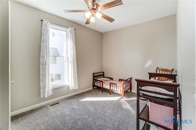 bedroom with a ceiling fan, baseboards, visible vents, a crib, and carpet flooring