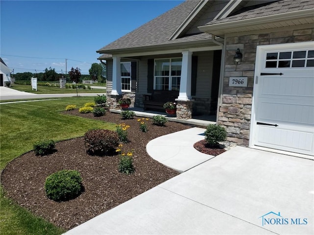 property entrance featuring stone siding, a porch, a yard, roof with shingles, and a garage