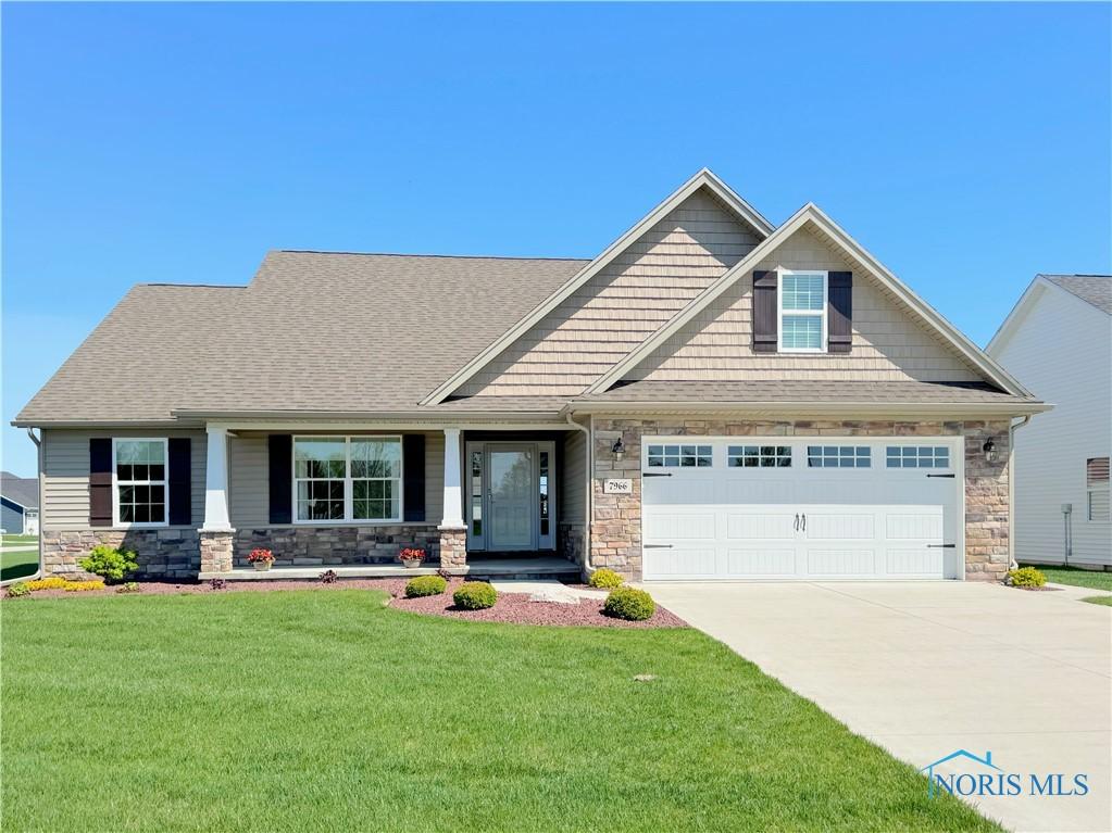 7966 Sonoma Dr, Monclova, OH 43542 - craftsman inspired home featuring a porch, a front lawn, stone siding, concrete driveway, and an attached garage