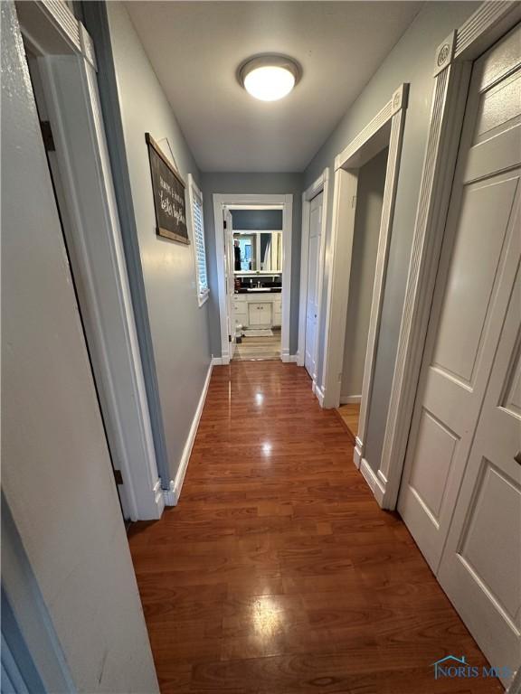 corridor with wood finished floors and baseboards