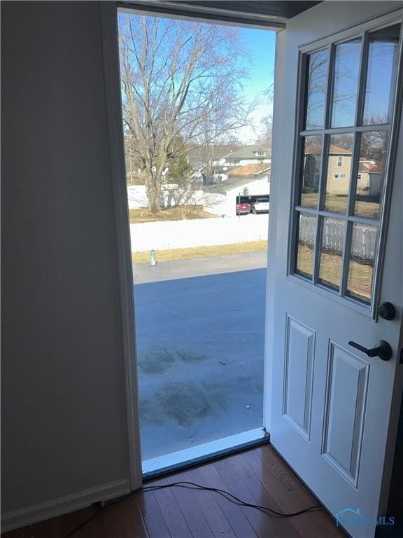 doorway with baseboards and dark wood finished floors