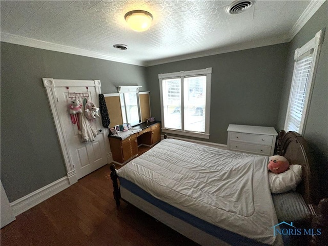 bedroom with visible vents, baseboards, wood finished floors, and crown molding