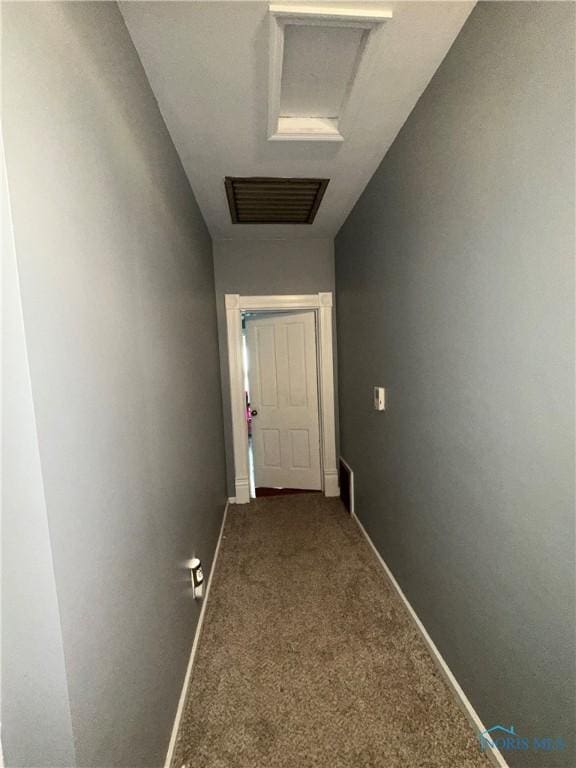 corridor featuring visible vents, baseboards, carpet, and attic access