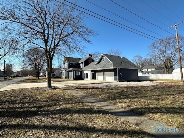 view of property exterior with fence, driveway, a chimney, a garage, and a lawn