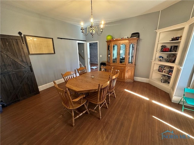 dining area with a barn door, baseboards, a notable chandelier, and wood finished floors