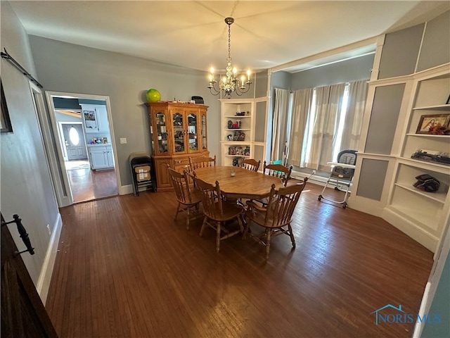 dining area with dark wood finished floors, a notable chandelier, a barn door, and baseboards