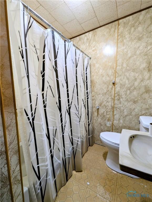 bathroom with tile patterned floors, toilet, and shower / tub combo with curtain