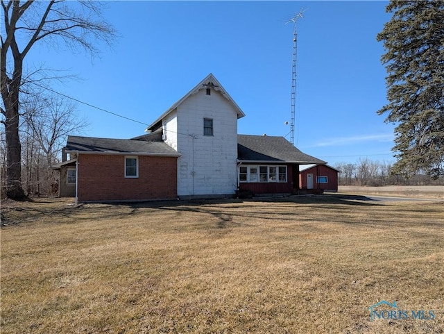 rear view of house featuring brick siding and a yard