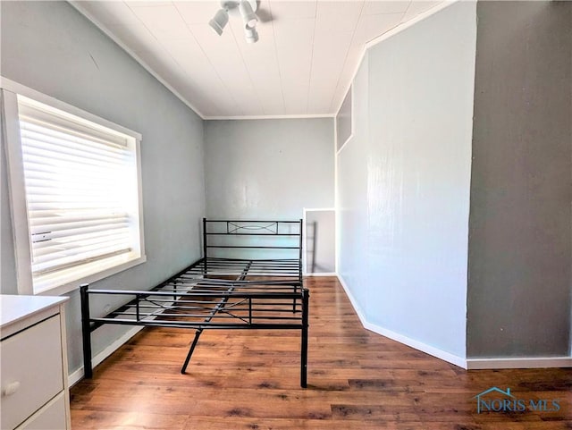 bedroom with crown molding, wood finished floors, and baseboards