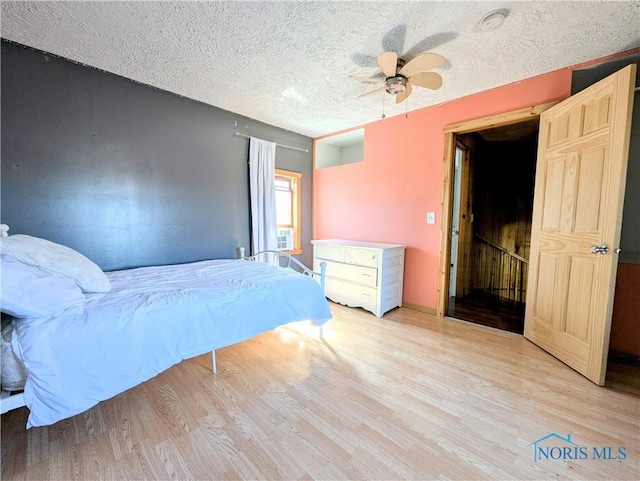 bedroom with a ceiling fan, light wood finished floors, and a textured ceiling