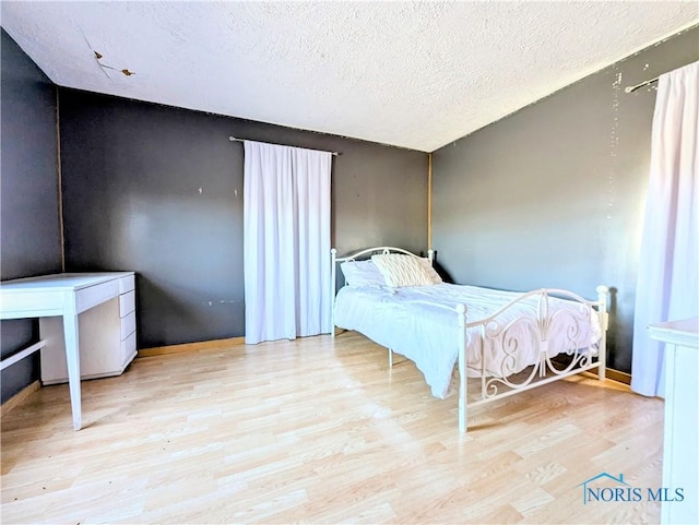 bedroom with a textured ceiling and wood finished floors