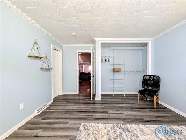 unfurnished room featuring baseboards, wood finished floors, visible vents, and ornamental molding