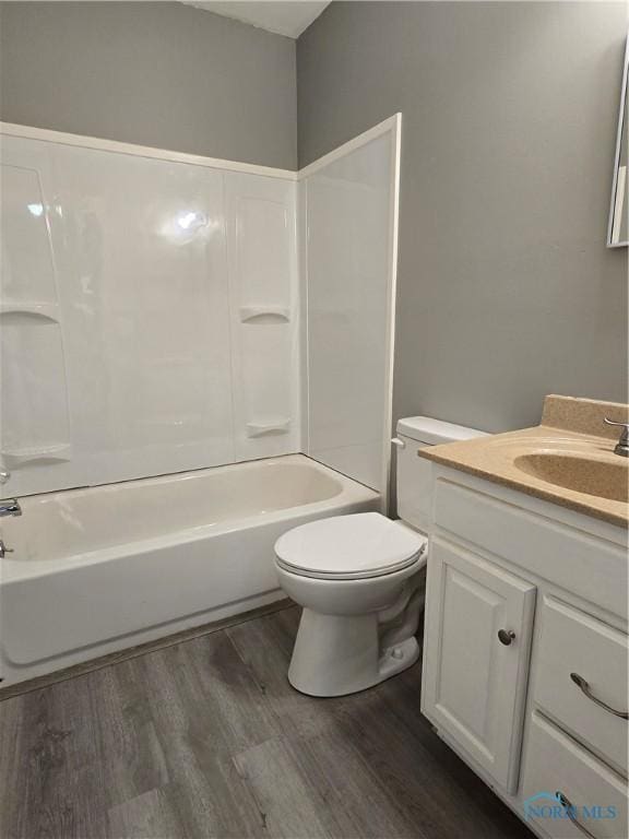 full bath with washtub / shower combination, toilet, wood finished floors, and vanity