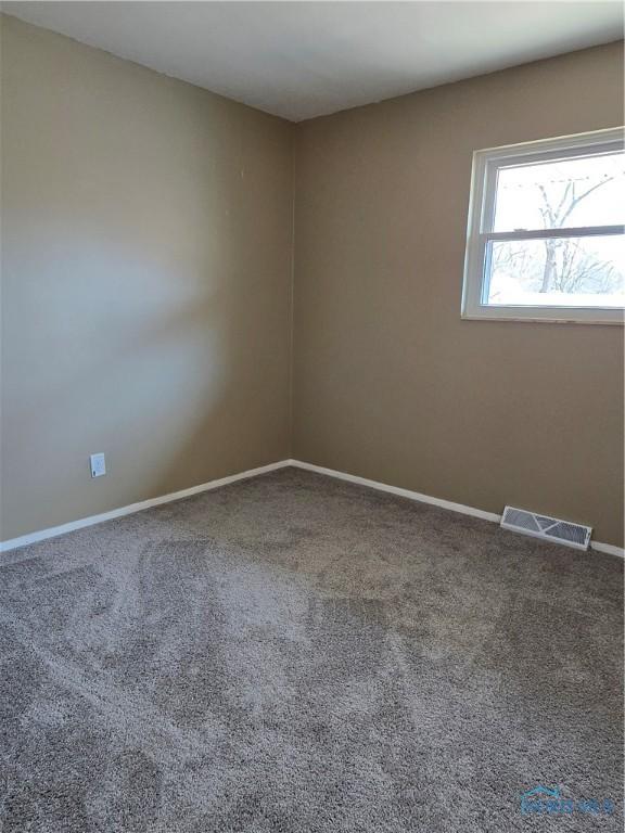 empty room featuring carpet flooring, baseboards, and visible vents